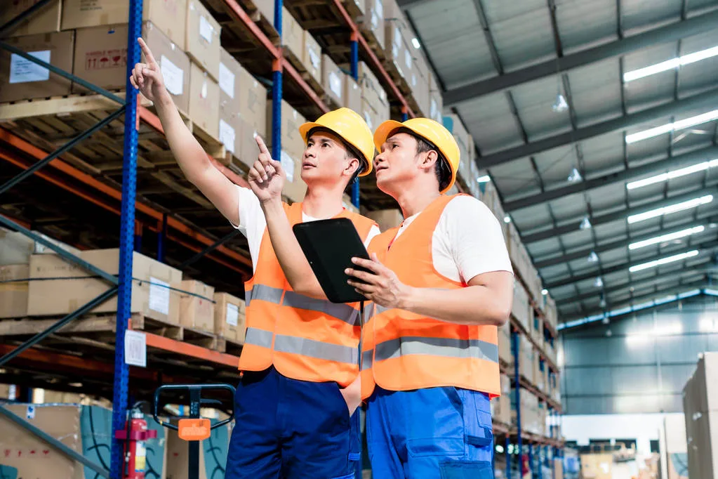 Workers in logistics warehouse at forklift checking list